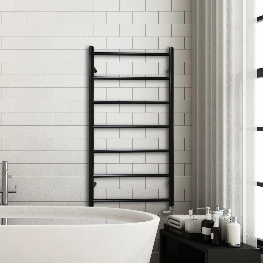 Lifestyle image of the The Sussex Range by JIS Pevensey 975mm x 520mm Black Heated Towel Rail installed on a white tiled wall, behind a freestanding bathtub